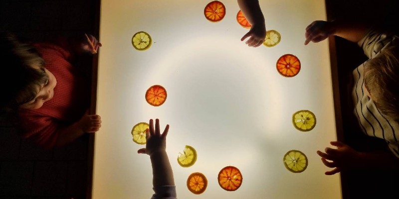 La lavagna luminosa con arance e mani di bambini
