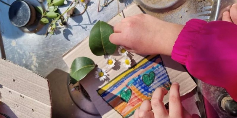 Foto di un bambini che crea una composizione con fiori e foglie
