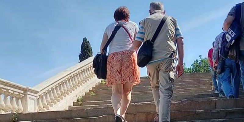 Due persone che si tengono a braccetto per salire una scalinata