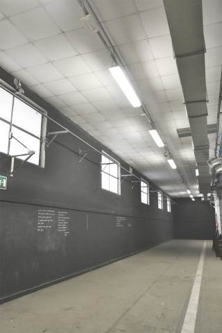 Foto del corridoio espositivo con pareti nere di Officina Giovani.