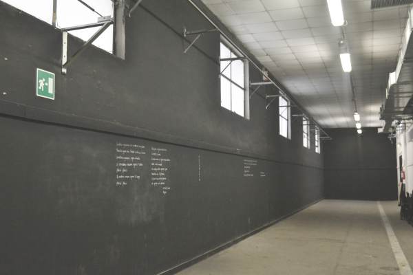 Foto del corridoio espositivo con pareti nere di Officina Giovani.