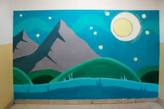 Murales alle Mazzoni con elementi naturali: montagne, prati e lago nei toni del verde e dell\'azzurro.