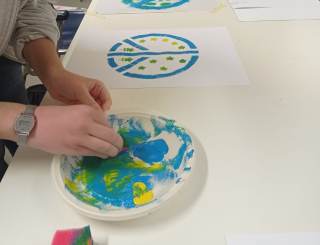 La ragazza colora il suo disegno con le tempere.