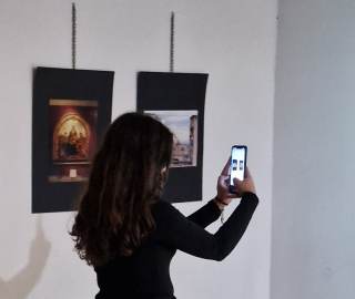La ragazza è vestita di nero e tiene il telefono in mano.