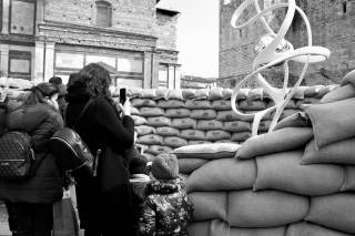 alcune persone fotografano dei sacchi davanti a loro