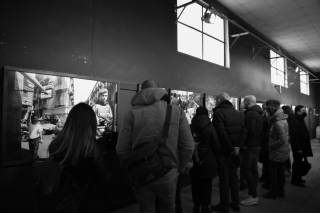 persone in piedi che guardano dei quadri ad una mostra