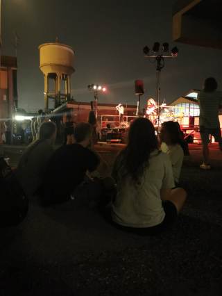 alcune persone sedute a terra mentre ascoltano un concerto