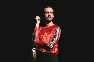 L\'attore nella foto utilizza un viso molto serio ed ha un braccio accavallato all\'altro.