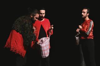 Gli attori, sul palco, giocano con la borsa.