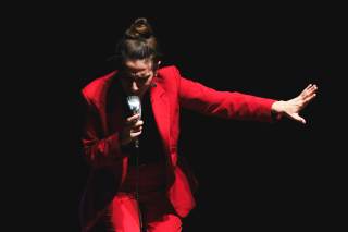 L\'attrice si piega in un inchino allungando il braccio.