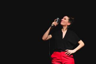 L\'attrice indossa una camicia nera e un pantalone rosso.