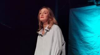 L\'attrice indossa una camicia bianca ed ha il rossetto rosso.