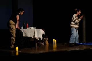 Foto dello spettacolo. Una delle due attrici parla, l\'altra la ascolta con espressione arrabbiata.