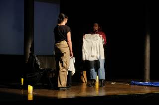 Foto dello spettacolo. Un\'attrice tiene in mano una maglia bianca.