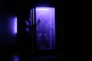 Foto dello spettacolo. Un attore &egrave; intrappolato in una piccola scatola, fatta girare dagli altri due attori.