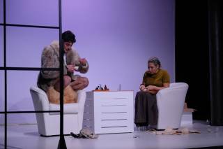 Foto degli attori sul palco. Stanno discutendo seduti su delle poltrone con in mano delle tazzine da caff&egrave;.