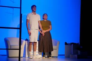 Foto degli attori sul palco. Entrambi gli attori in piedi davanti agli spettatori si tengono per mano.