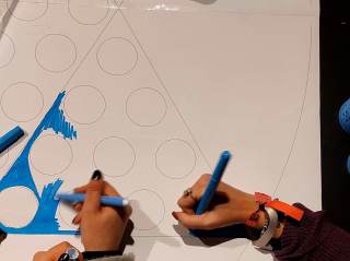 Foto di ragazzi e ragazze che colorano sulla carta durante il laboratorio.