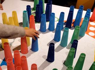 Foto di ragazzi e ragazze che giocano sulla plancia da gioco che hanno creato durante il laboratorio.