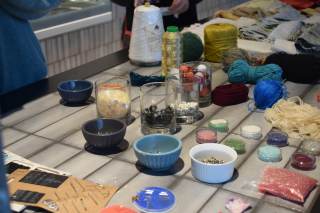 Foto di vari strumenti per cucire, tessuti e bottoni su un tavolo.