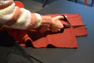 Foto di un partecipante che taglia del tessuto con delle forbici durante il laboratorio