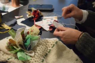 Foto di un partecipante intento a ricamare e cucire un capo d\'abbigliamento durante il laboratorio