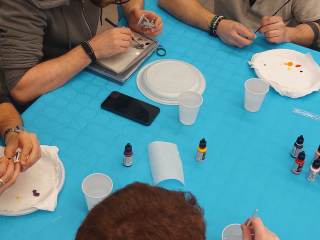 Dei partecipanti al laboratorio dipingono delle miniature