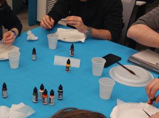 Dei partecipanti al laboratorio dipingono delle miniature