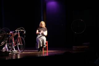 Foto dello spettacolo. Un\'attrice &egrave; intenta a cucire.